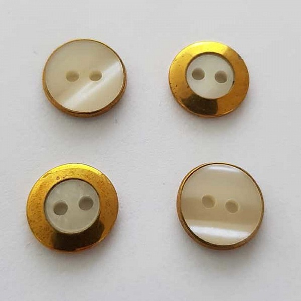 Quatre boutons ronds dorés avec centre nacré à deux trous.