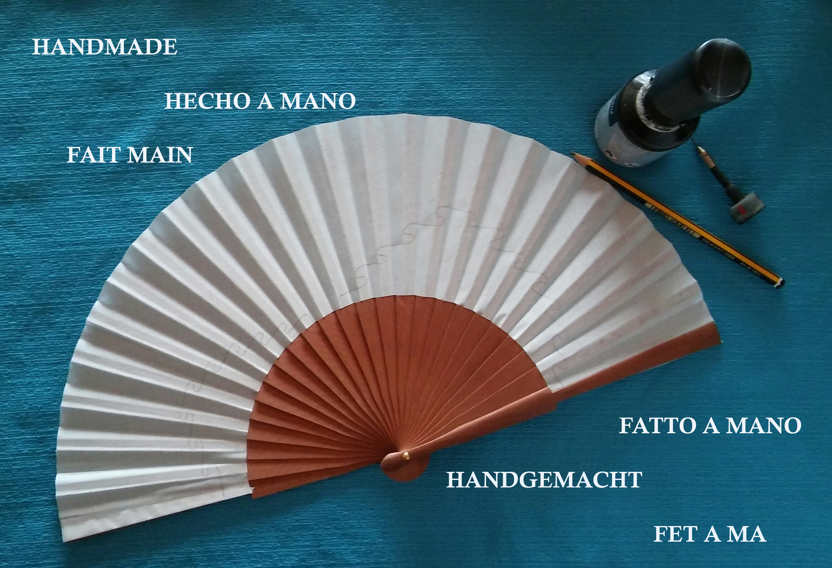 Éventail en satin peint à la main avec outils artisanaux.