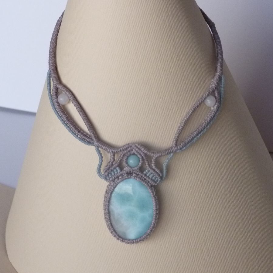 Collana in micro-macramè grigio tortora/blu smerigliato con al centro una gemma naturale nei toni tenui del bianco e dell'azzurro.