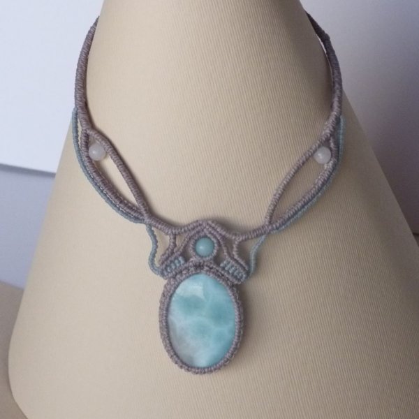 Collana in micro-macram&egrave; grigio tortora/blu smerigliato con al centro una gemma naturale nei toni tenui del bianco e dell'azzurro.