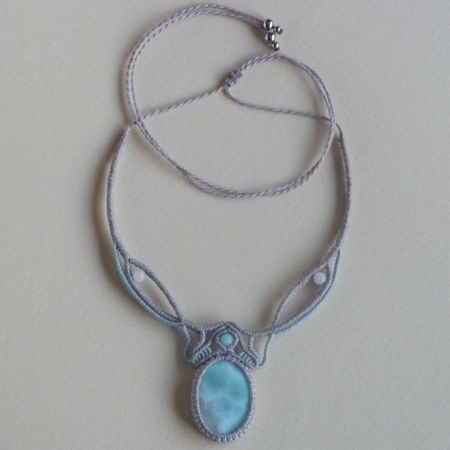 Collana in micro-macramè grigio tortora/blu smerigliato con al centro una gemma naturale nei toni tenui del bianco e dell'azzurro.