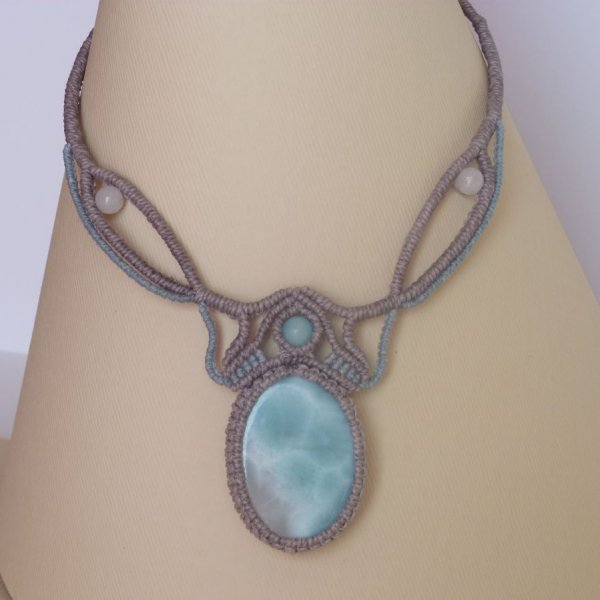 Collana in micro-macram&egrave; grigio tortora/blu smerigliato con al centro una gemma naturale nei toni tenui del bianco e dell'azzurro.
