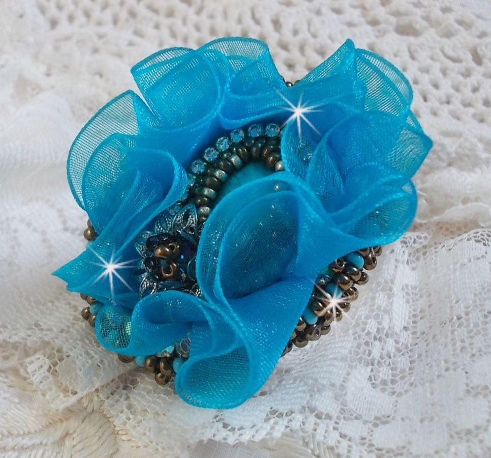 Ilycia Incantevole anello ricamato con un cabochon di resina blu turchese sfaccettato e un nastro di organza