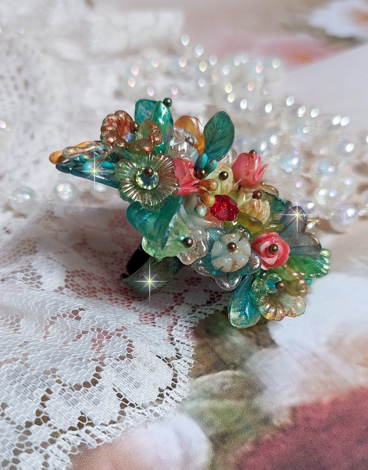 Bague Patiflo d&rsquo;une composition florale cr&eacute;&eacute;e avec des cristaux, fleurs en R&eacute;sine, perles, clochettes, pens&eacute;es, boutons de rose en Verre, estampes et coupelles. Le tout est mont&eacute; sur une bague estampe