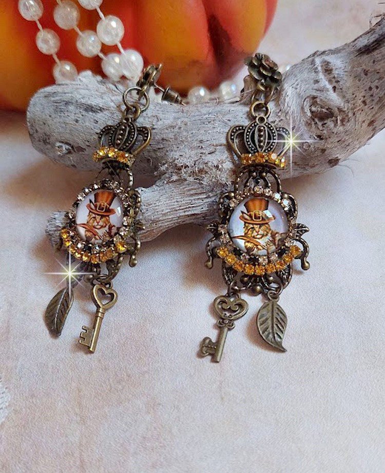 BO Chatibo Steampunk montées avec cabochons ronds en verre représentant un chat chapeauté Haute de Forme Orange. Strassées avec une couronne, breloques clés et feuilles. Montées sur clips Bronze