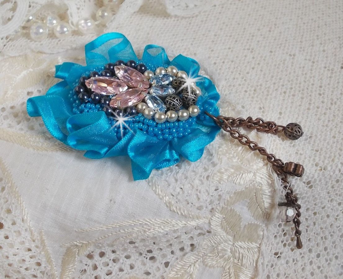 La spilla Belle Epoque Haute-Couture è ricamata con cristalli Swarovski, perle rotonde, ciondoli, nastri e perline.