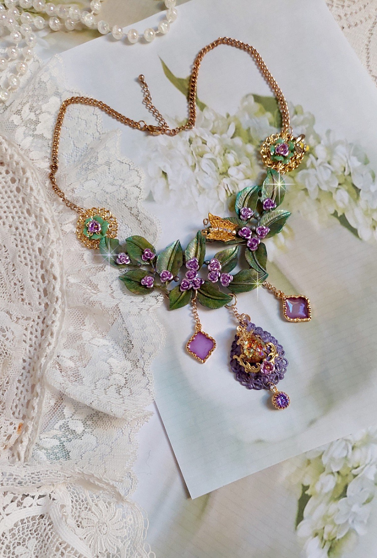 Collier Camélia Japonica monté avec un motif feuilles aquarellés à la main, paillettes, breloques papillons et abeille, roses métal, cabochon cristal, pendentifs époxy aux couleurs d’arc en ciel