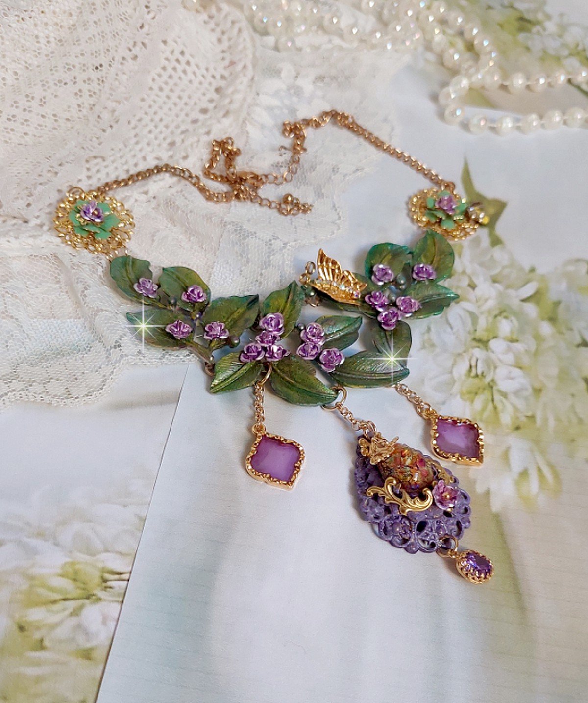 Collier Camélia Japonica monté avec un motif feuilles aquarellés à la main, paillettes, breloques papillons et abeille, roses métal, cabochon cristal, pendentifs époxy aux couleurs d’arc en ciel