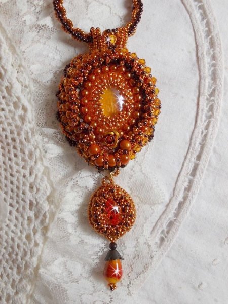 La collana con ciondolo Lady in Orange &egrave; ricamata con cristalli Swarovski, perline Miyuki e perline magiche.