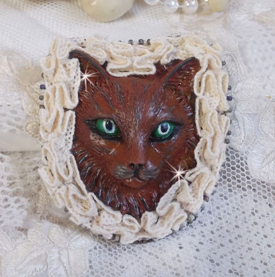 Masque Chat Rocky aux Yeux Verts tout en Fimo brodé avec un dentelle beige très fine, des perles rondes nacrées en Cristal de Swarovski, de la peinture et des rocailles