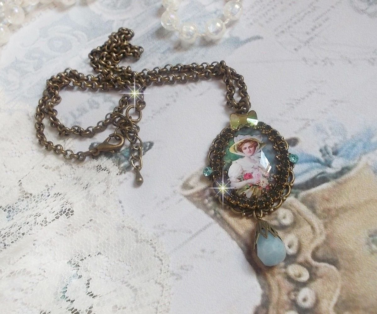 Pendentif Douce Dame créé avec un cabochon représentant une femme au chapeau blanc orné de cristaux, des accessoires de couleur Bronze et un jade teinté bleu 