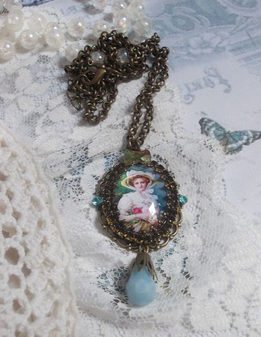 Pendentif Douce Dame créé avec un cabochon représentant une femme au chapeau blanc orné de cristaux, des accessoires de couleur Bronze et un jade teinté bleu 