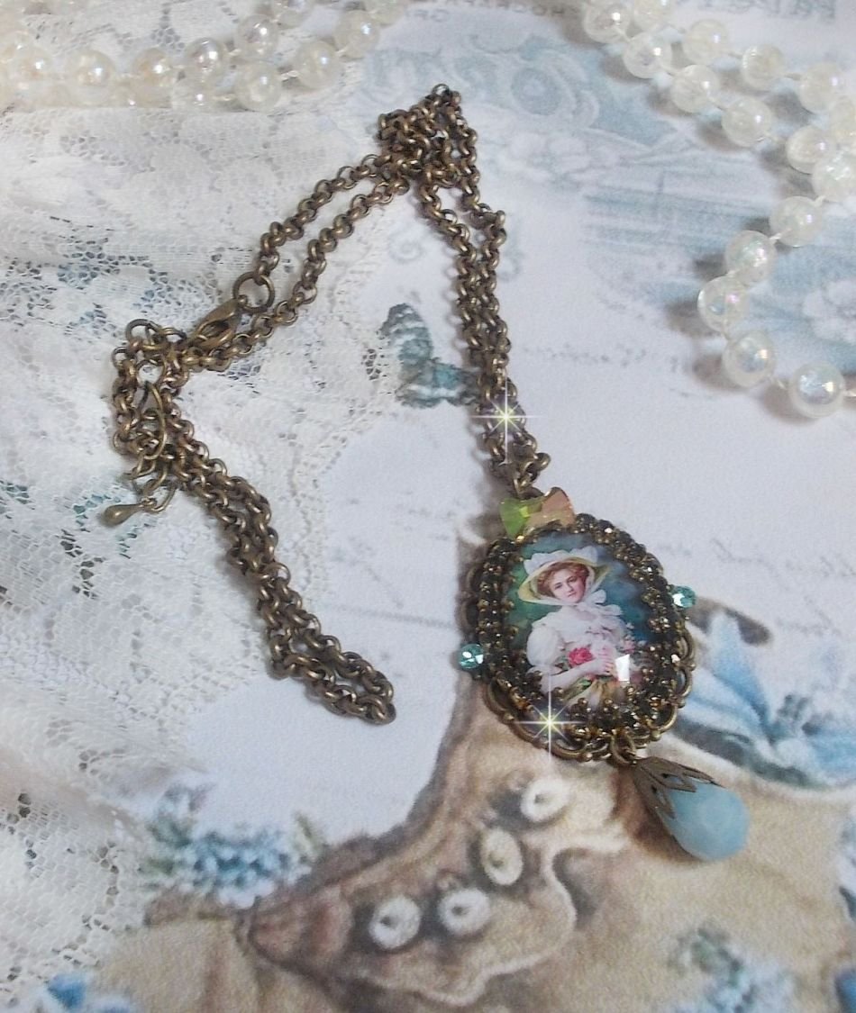 Pendentif Douce Dame créé avec un cabochon représentant une femme au chapeau blanc orné de cristaux, des accessoires de couleur Bronze et un jade teinté bleu 