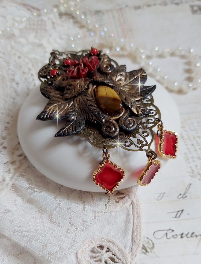 Pendentif Mélodie avec un cabochon Œil de tigre orné de perles en Jade Rouge veiné de Noir sur fleurs 5 pétales et estampes montés sur une chaîne bronze. Les pendants sont en résine époxy Rouge