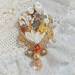 Pendentif Aurore monté avec un motif émaillé aux couleurs du soleil à laquelle s’ajoute perles nacrées, breloques, poires avec Zircons, perles, ruban sur une bélière Argent 925 et une chaîne plaqué Or