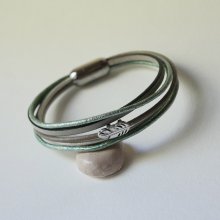Bracciale in pelle multipla nei toni del beige, del verde chiaro e del perlato, decorato con una piccola piuma